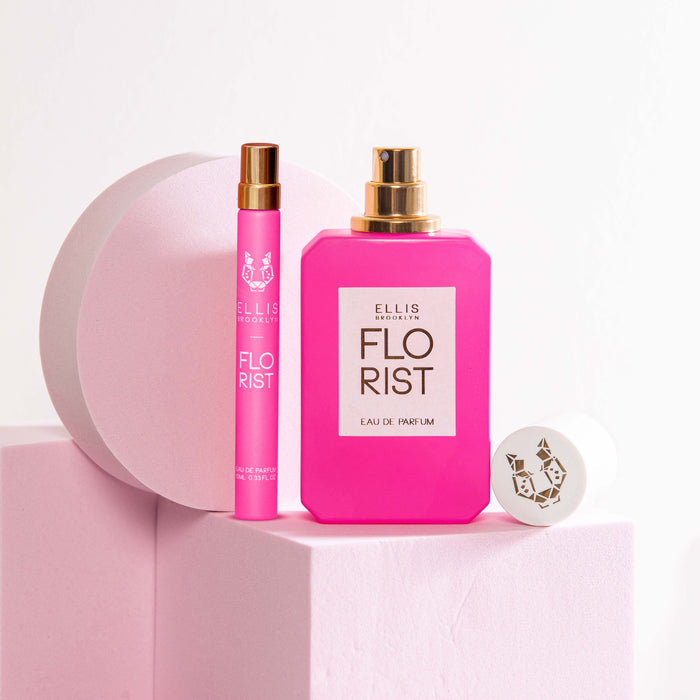Florist 10ml Eau De Parfum Travel Spay next to Florist 50ml Eau De Parfum with cap removed on light pink block, next to light pink circle prop and light pink square prop, on light pink background.