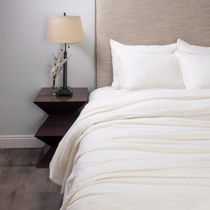 Neatly made bed with neutral linen bedding in a bedroom setting. | Wildwood Home Co.