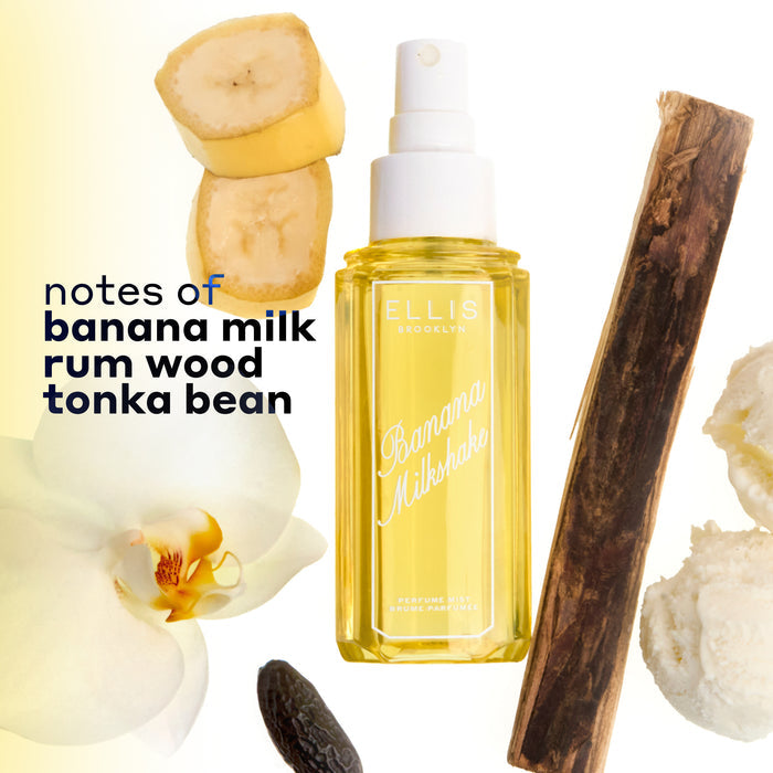 BANANA MILKSHAKE Perfume Mist 240ml  without a cap surrounded by 2 slices of banana, a piece of rum wood, 2 scoops of vanilla ice cream, a tonka bean, and a flower on a white and yellow ombré background with black text that reads "notes of banana milk, rum wood, tonka bean"