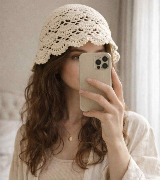 Ivory crochet lace cap with open floral knit, worn with brim edge and scalloped trim.
