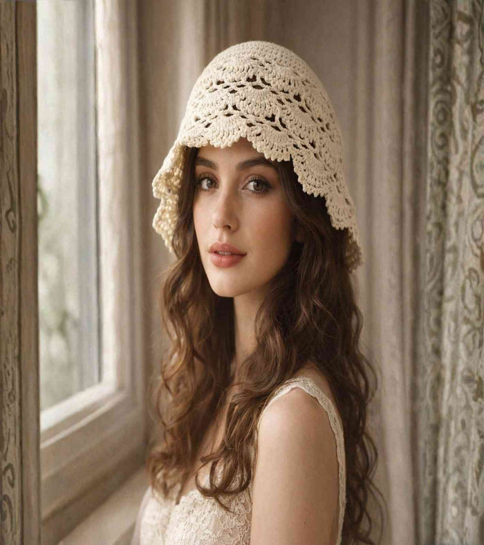 Ivory crochet lace cap, open floral knit with scalloped brim, worn at an angle.