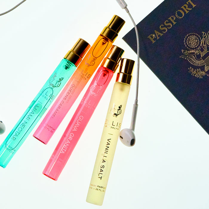 GUAVA GRANITA Eau de Parfum 10ml, MIAMI NECTAR Eau de Parfum 10ml, QUEENS CARAMEL Eau de Parfum 10ml, and VANILLA SALT Eau de Parfum 10ml next to a pair of headphones and passport on a white background