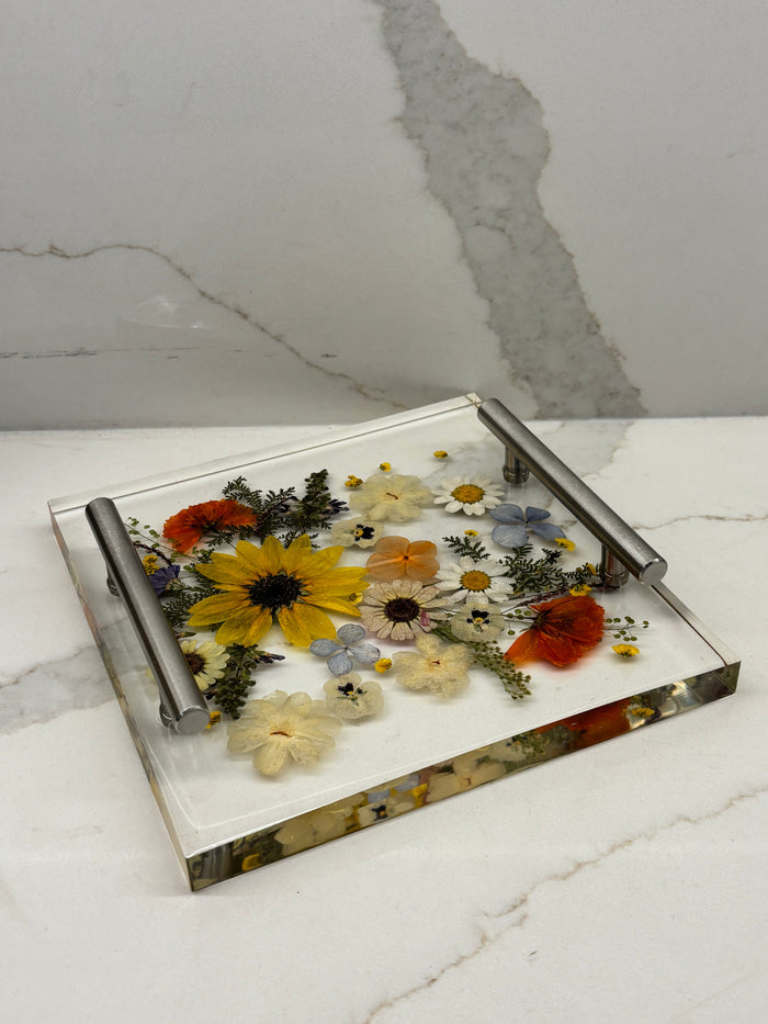 Square clear resin tray featuring a beautiful arrangement of embedded dried yellow and red flowers with metallic accent handles.