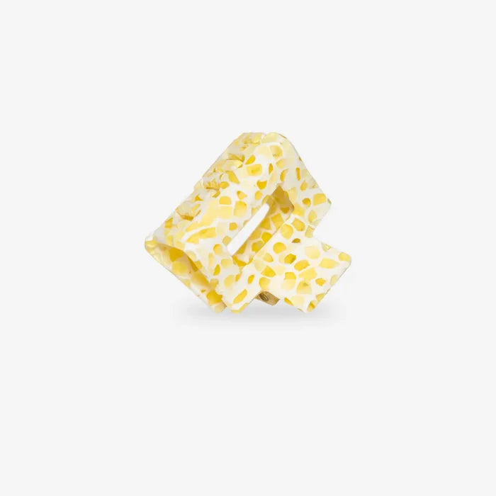 Yellow polka dot hair clip on a white background