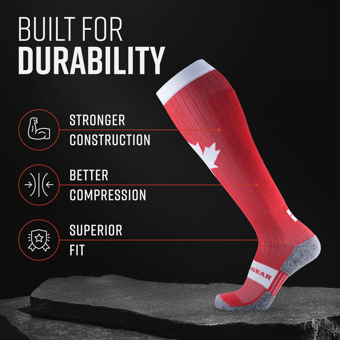 Red and white compression sock with Canada Maple Leaf logo, gray heel and toe, displayed on dark surface
